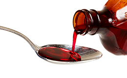 A bottle of cold medicine poured into a spoon